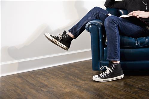 Person with leg on arm of chair reading